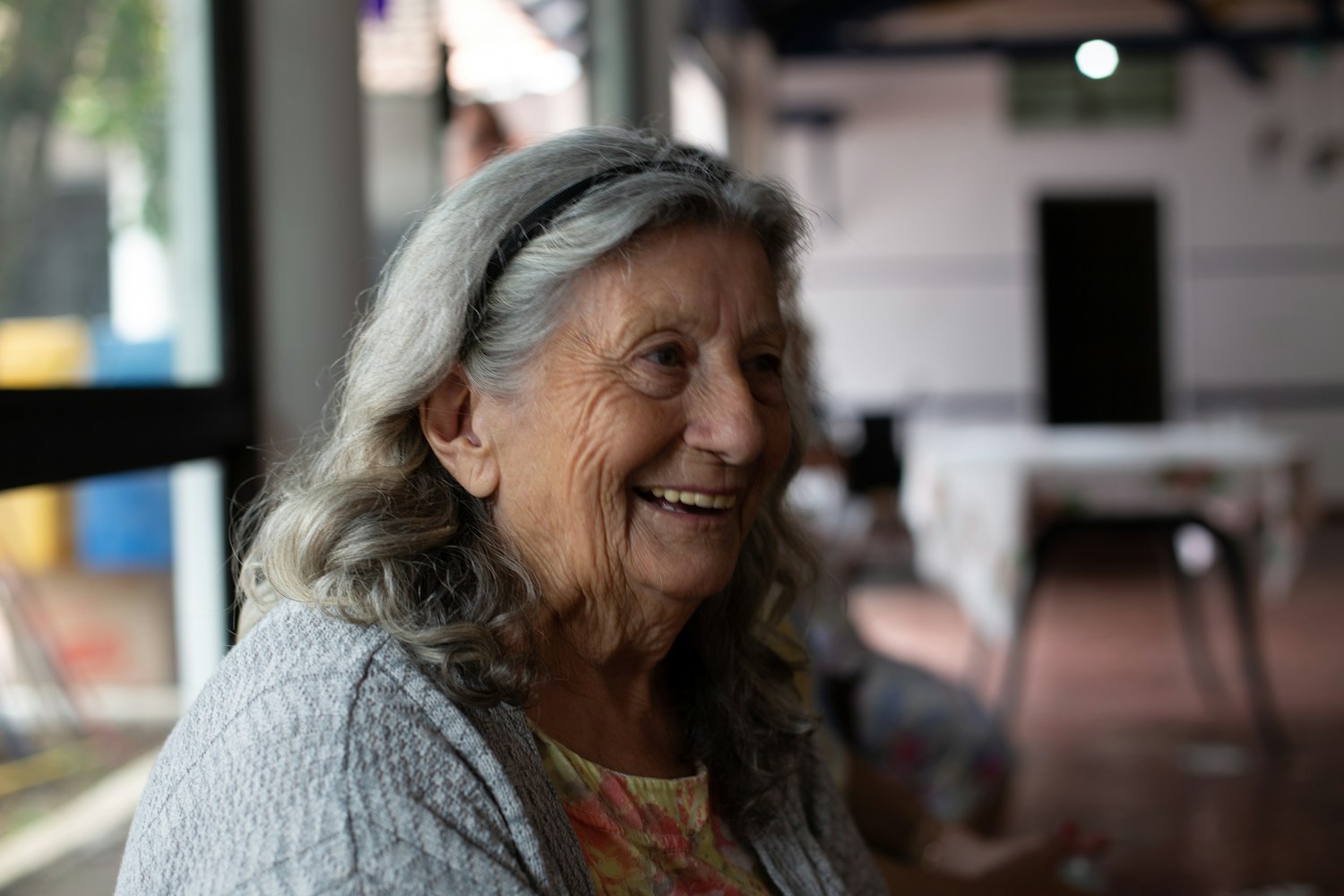 Senhora idosa sorrindo, sentada em casa